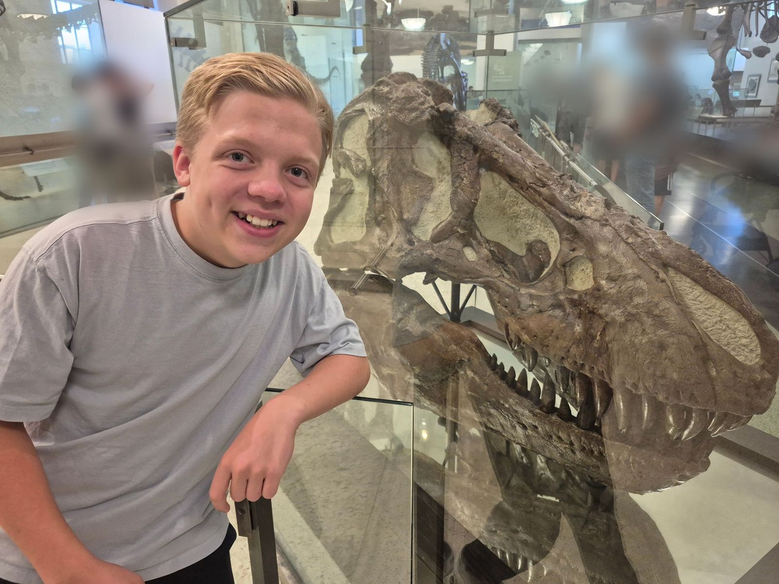 Henry leaning beside a huge dinosaur skull in a museum