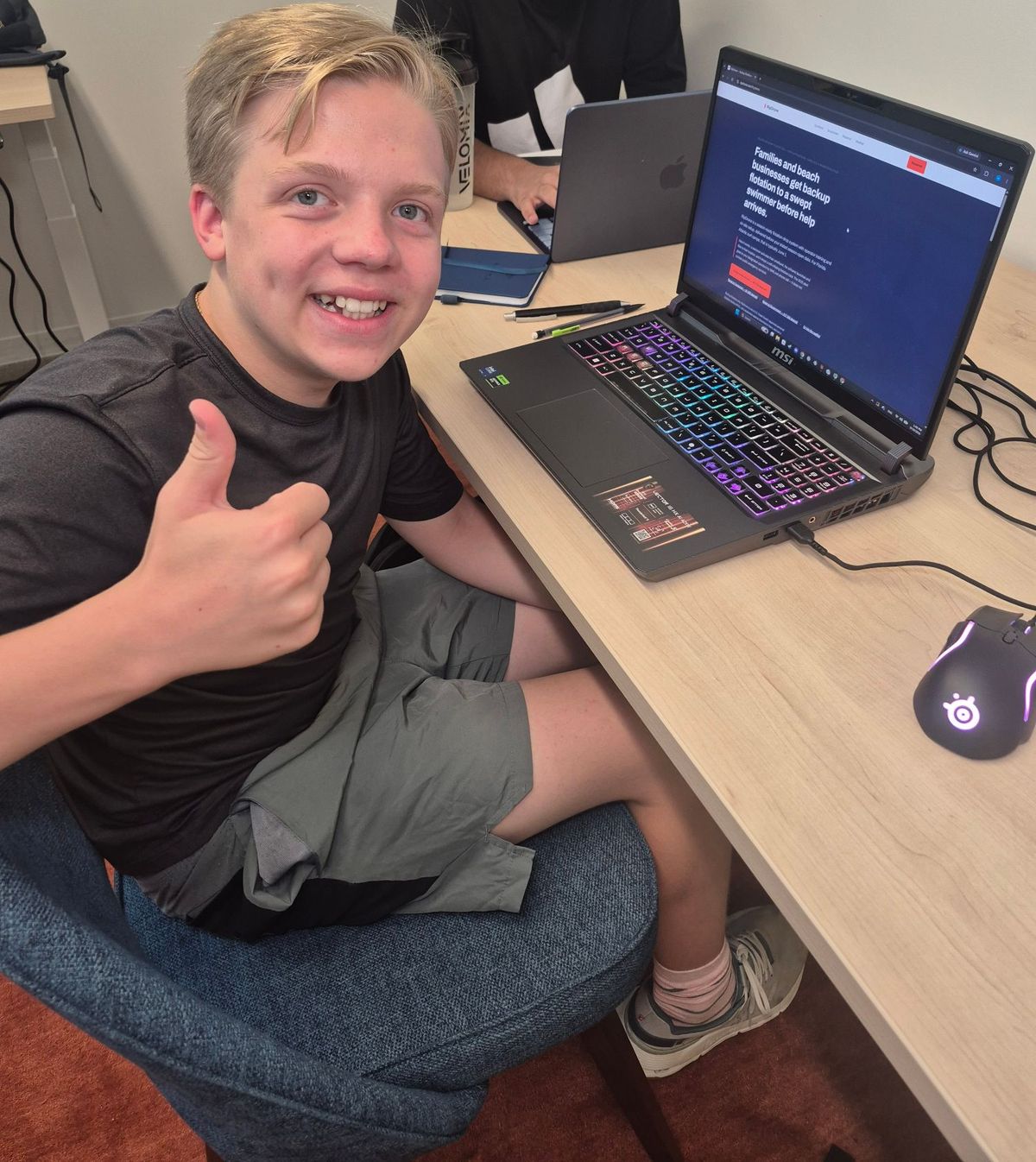 Henry giving a thumbs-up at a desk, with the RipDrone website open on his laptop